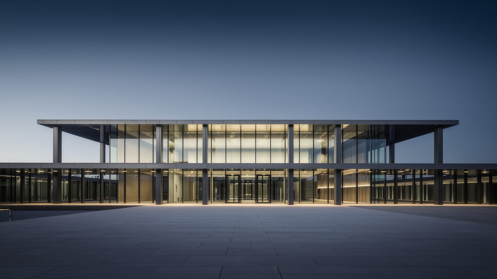 Un edificio istituzionale europeo dalla facciata in vetro e acciaio al crepuscolo, immagine della governance e della vigilanza che accompagnano le nuove regole sull'AI ad alto rischio