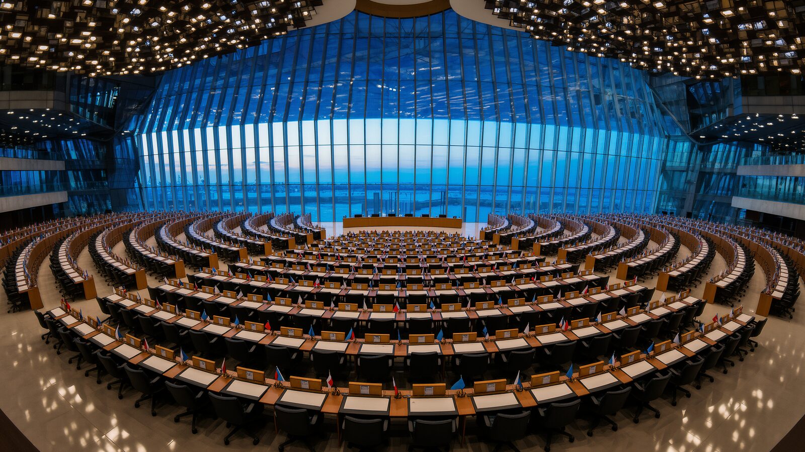 Sala plenaria di una grande conferenza internazionale sull'intelligenza artificiale al tramonto, con file di banchi per i delegati, segnaposto e stand delle bandiere, architettura in vetro e acciaio