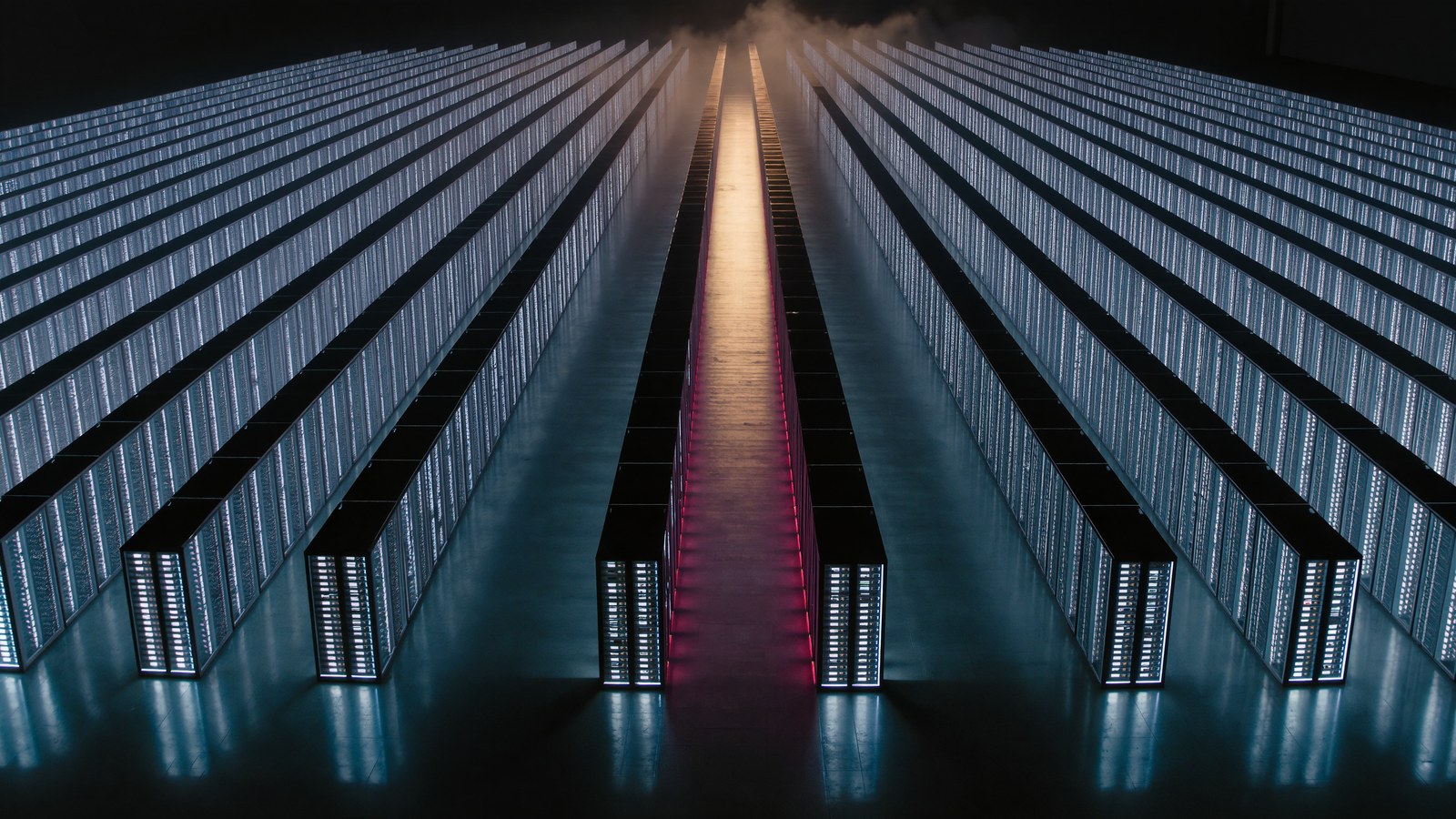 Sala dati moderna con lunghe file di rack server illuminati: la classe di infrastruttura su cui la capacità di calcolo raggiunge il proprio limite